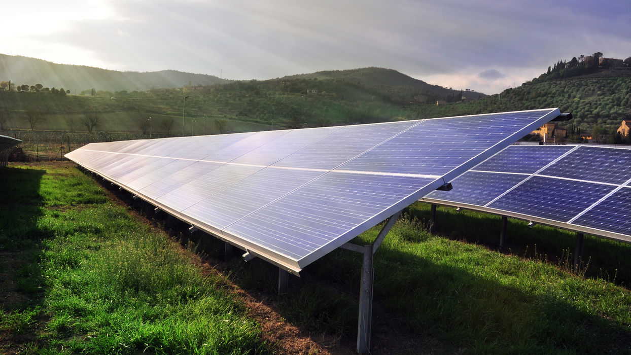 Solar panels in a green field with distant hills