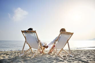 romantic happy couple on deckchair relaxing and enjoying sunset on the beach