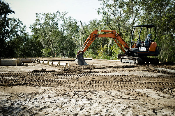Tracked digger levelling stone sub-base on a prepared construction site