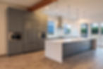 Modern kitchen featuring grey cabinetry, a large white island, and pendant lighting