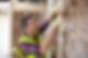 Builder wearing a high-visibility vest and safety helmet installing insulation rolls onto a wall