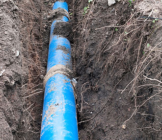 Blue water pipe laid in a trench surrounded by soil during groundworks