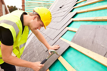 roofer on building site laying slate tiles