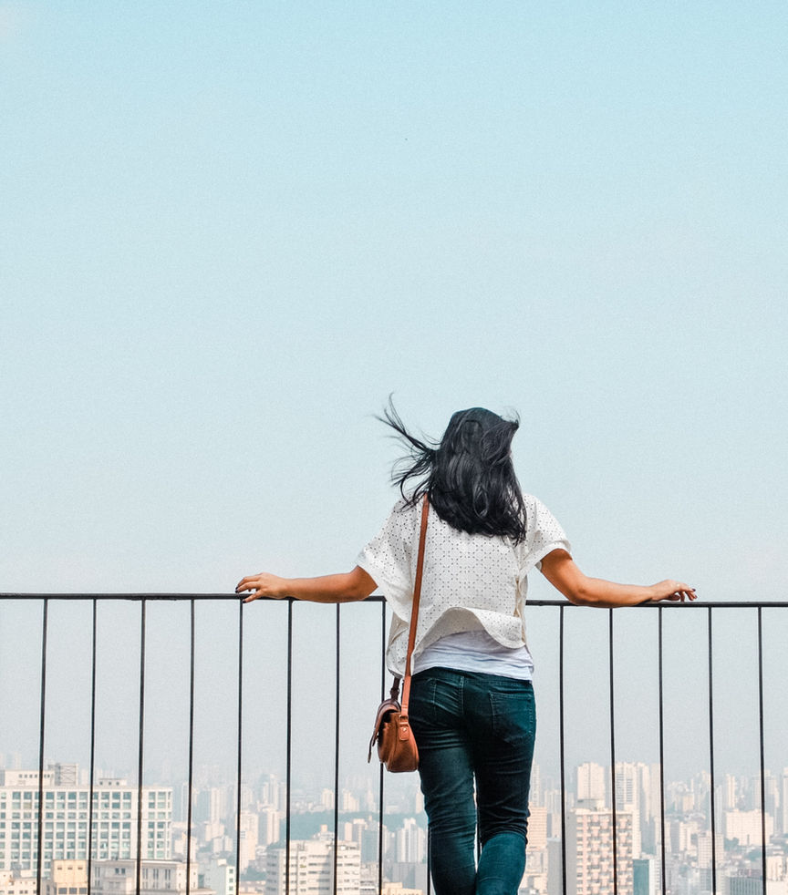 Une femme seule contemple la ville depuis une terrasse en hauteur, image évoquant le calme, la réflexion et la valeur du temps passé seul dans la culture japonaise.