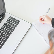 Girl taking note next to a laptop