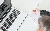 Girl taking note next to a laptop
