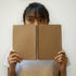 Woman hiding behind her notepad looking sideways