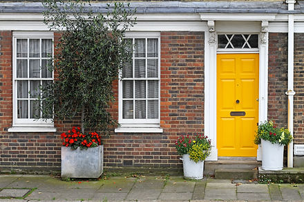 Old English house with brick wall and yellow door