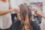 A woman with curled hair in a salon, as stylists prepare her hairstyle