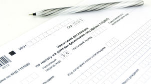 Typewriter with a sheet labeled TAX RETURN, set against a blurred green background.