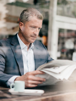 Üzletember olvas újságot egy kávézóban – Digitális fejlődési lehetőségek KKV-k számára a 'Minden vállalkozásnak legyen saját honlapja' program keretében.