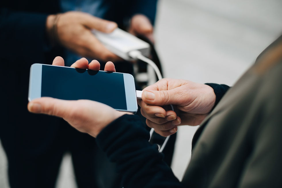 Person holding smartphone while connected to portable power bank charging system