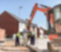 Builders using digger to lift kerb stones on housing building site