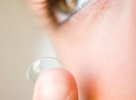 Contact lens use. Woman inserting a disposable (soft) contact lens
