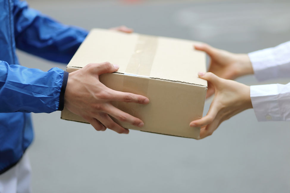 Close-up of hands passing a cardboard parcel box between two individuals
