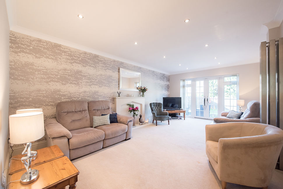 A general view of a lounge, living room with sofa, arm chair looking toward patio doors in