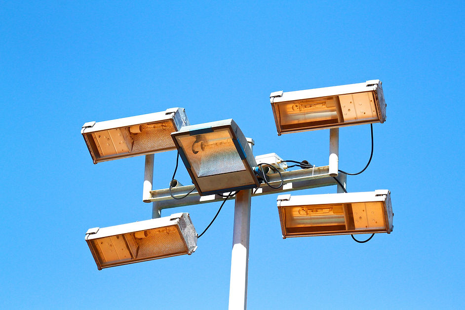A cluster of five street lights on a pole against a clear blue sky