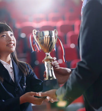 A public speaking student receiving a reward trophy at the end of a competition