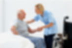 A female caregiver helping senior man get up from bed