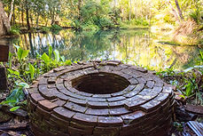 Red brick well in the middle of a pond