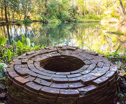 Puits en briques rouges au milieu d’un étang
