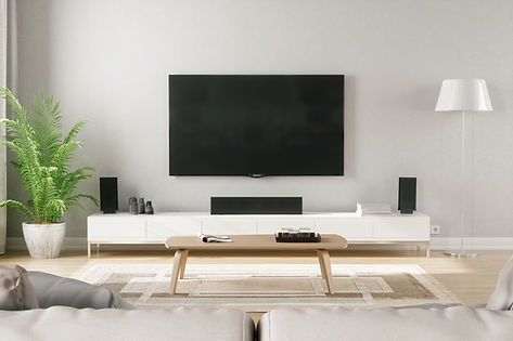 Modern living room with a large TV on a white stand, surrounded by speakers