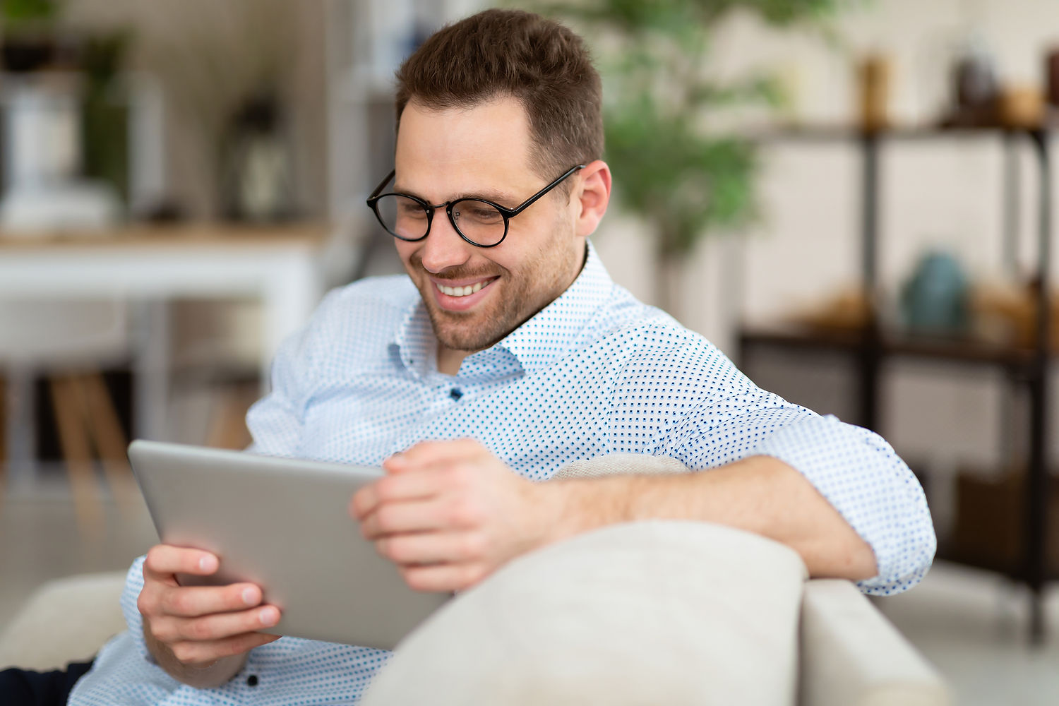 Un homme souriant regarde une tablette