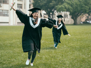 Two graduates celebrating outdoors.
