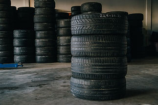 Stacks of black car tyres are arranged garage