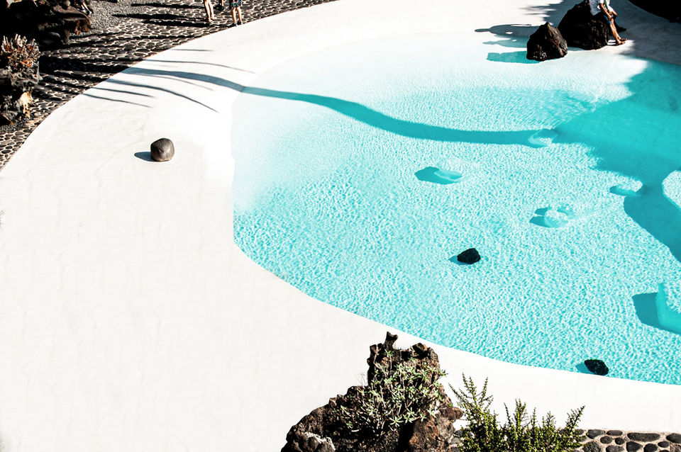 Modern pool with turquoise water, white concrete, and dark rocks