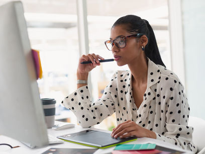 Woman working thoughtfully at a computer in an office.