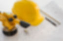 Hard hat and surveying equipment on blueprints
