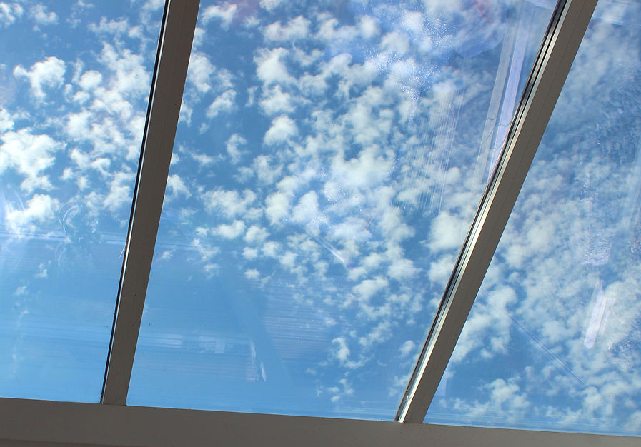 Photo showing a white UPVC conservatory that features a modern glass roof, with tinted win