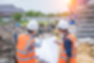 workers review blueprints at a construction site