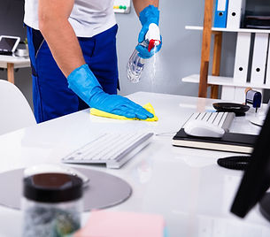A cleaner wearing gloves while cleaning an office workstation.
