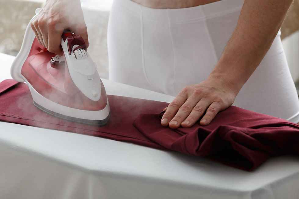 Male in white underwear ironing marsala colored trousers