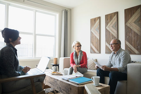 Financial advisor with laptop meeting with senior couple in living room