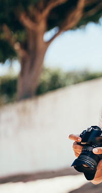 Mockup eines Smartphones, das die Hände eines Fotografen zeigt, der eine Kamera in Händen hält.