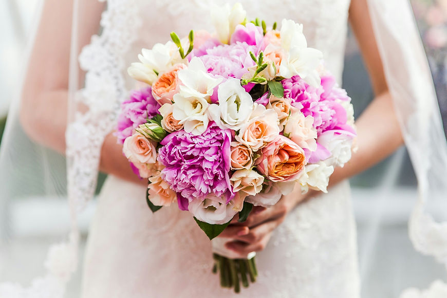 Bride in a white gown holding a vibrant pink and purple bridal bouquet