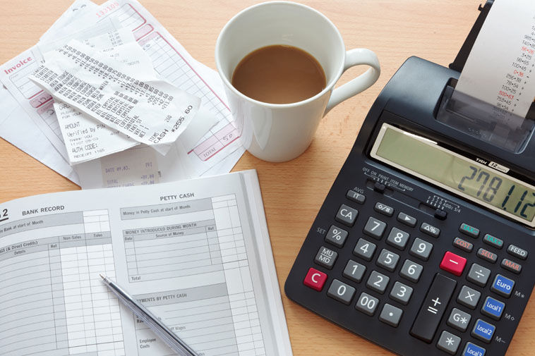 Still life bookkeeping photo of a sales ledger with a pile of receipts, invoices and a pri