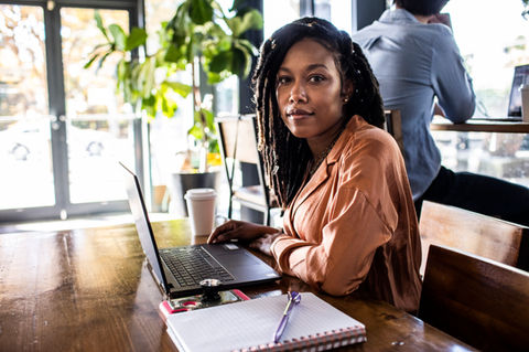 A woman sitting at a desk in front of a laptop.