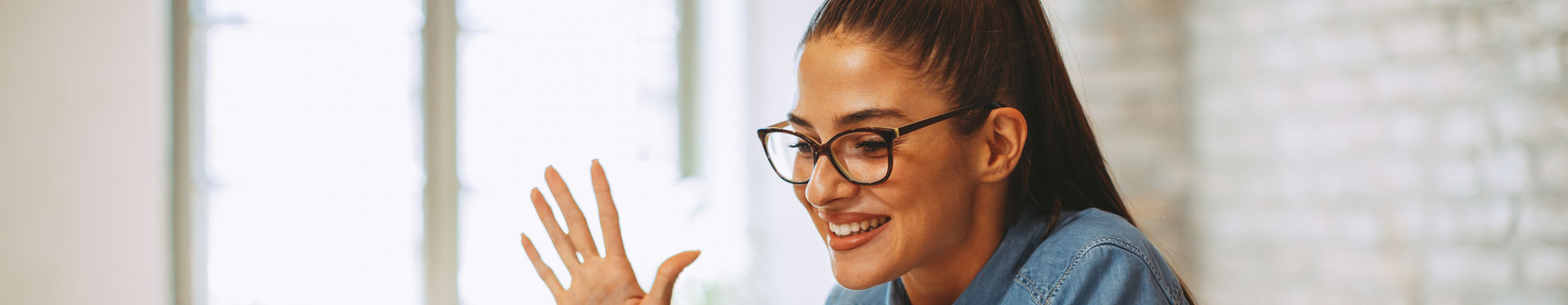 Smiling woman waves hello during video conference call