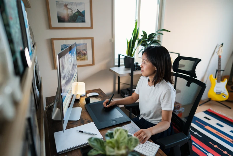 Professional working from a comfortable home office setup with a laptop, coffee mug, and ergonomic chair