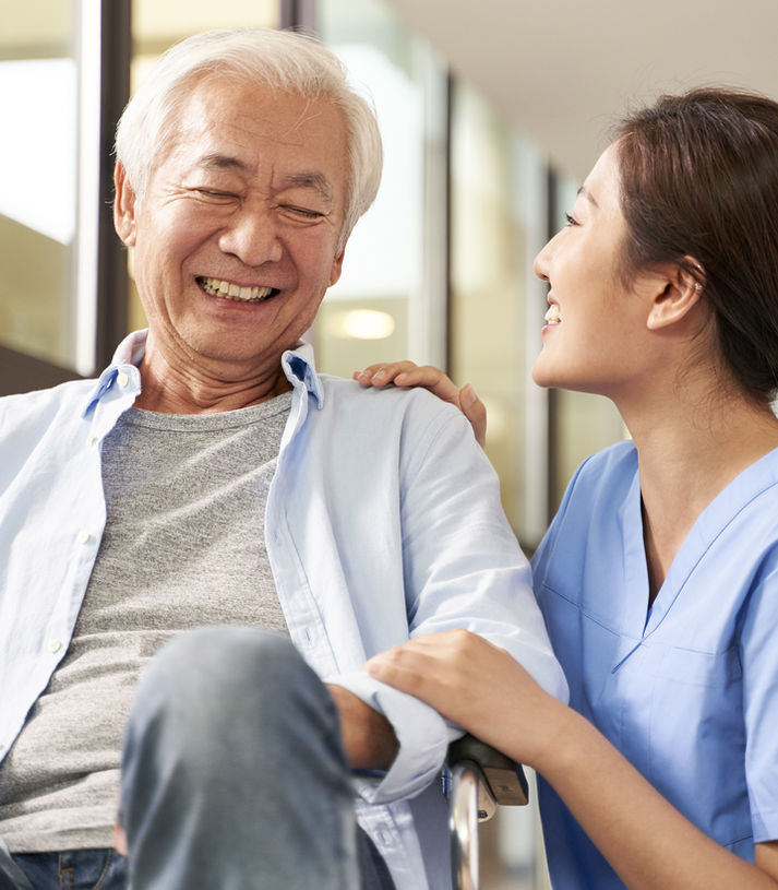 Smiling senior man in a wheelchair with a female caregiver