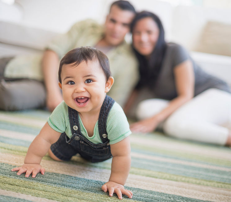Baby crawling with parents watching
