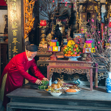 A person’s hands gently placing a small glass of water onto a serene, minimalist wooden table decorated with a burning white candle, a bowl of crystals, and a small incense burner with a soft trail of smoke.