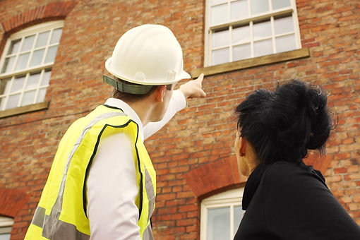 A property surveyor standing in front of a property with the homeowner, pointing to an issue with the first floor window