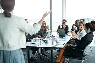 A group of business professionals sits around a table in a bright conference room