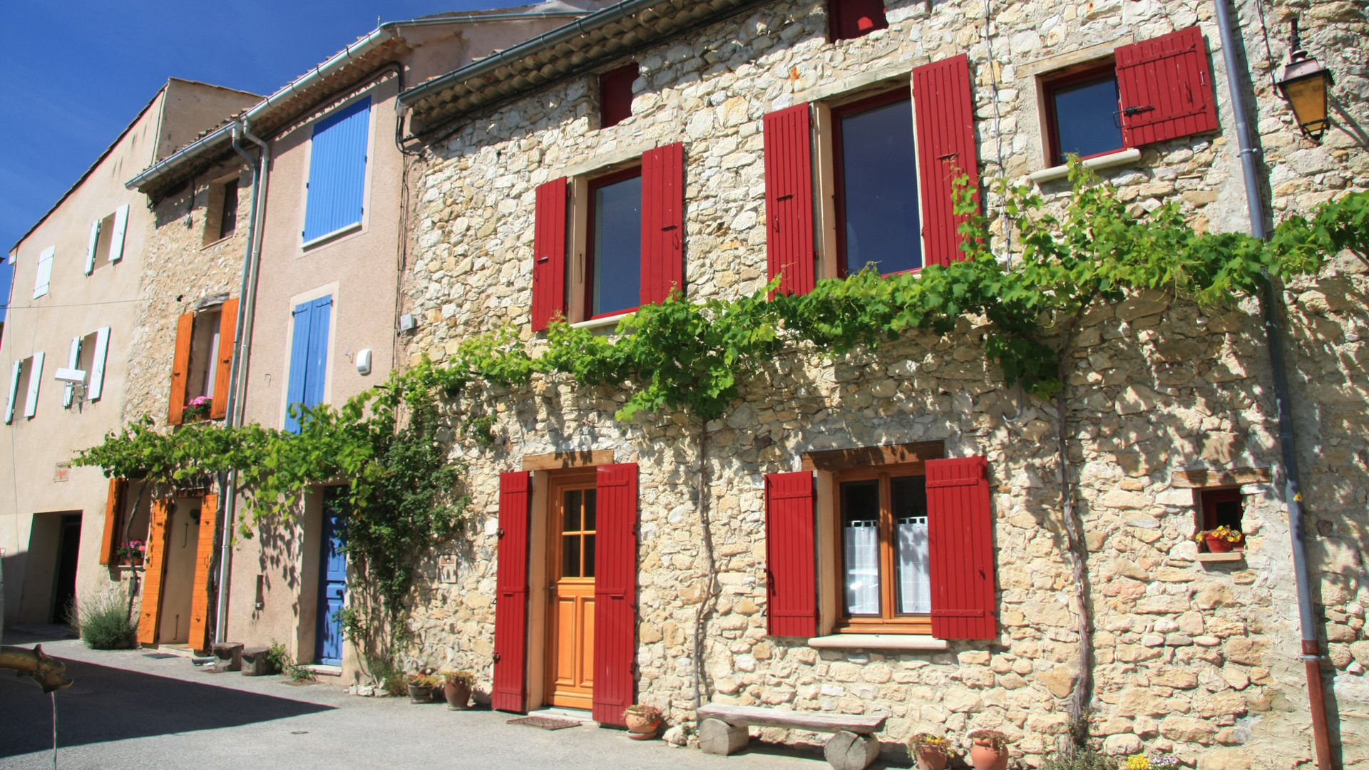 Façade en pierre aux volets rouges d'un village perché de Provence
