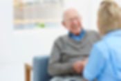 Happy elderly patient talking with nurse at home